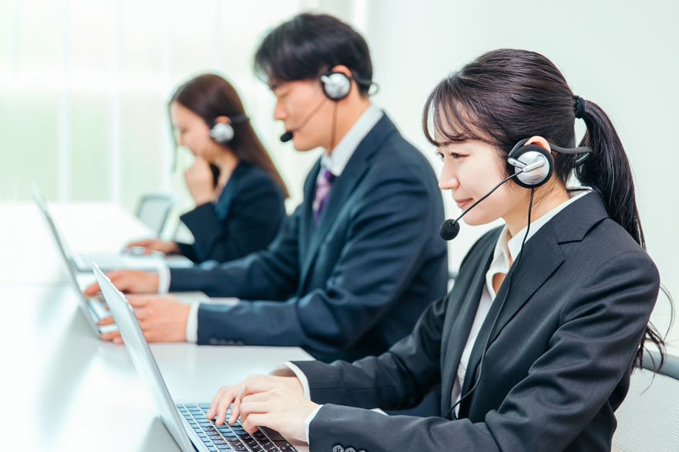 ヘッドセットを着けたスタッフが電話とフォームの相談に対応している様子